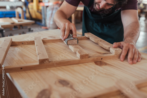 Craftsman skillfully sanding a piece of wood in his workshop