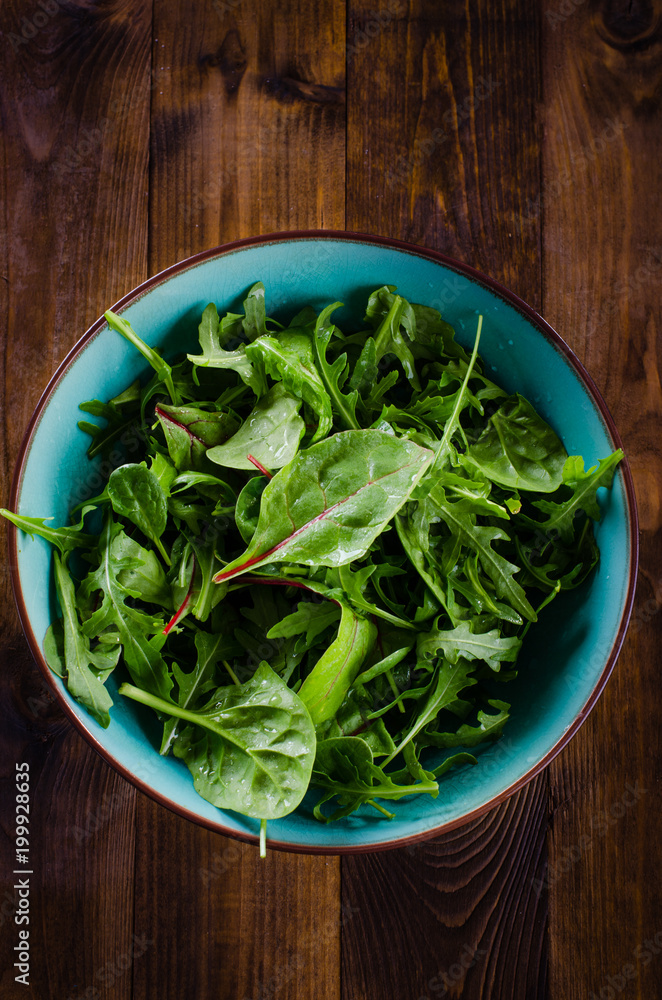 Fresh green salad with spinach,arugula, mangold and lettuce on dark wooden background Fresh green salad with spinach,arugula, mangold and lettuce on dark wooden background