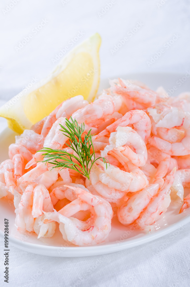 shrimps - cooked and peeled with lemon wedge on white shrimps - cooked and peeled with lemon wedge on white