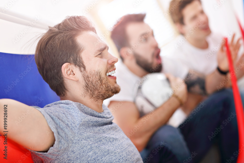 Happy male friends cheering and watching sports on tv Happy male friends cheering and watching sports on tv