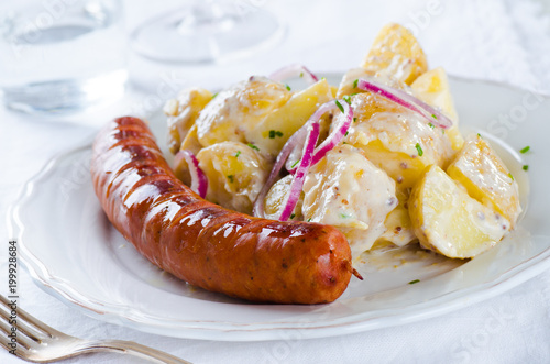 grilled sausage with classical potato salad with mayonnaise dressing on white backgound