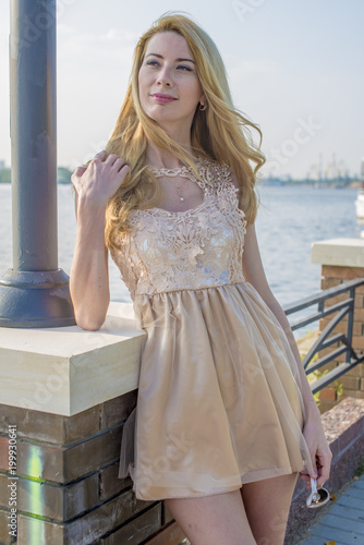 Young beautiful blond woman in a beautiful dress on the waterfront

