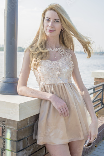 Young beautiful blond woman in a beautiful dress on the waterfront 