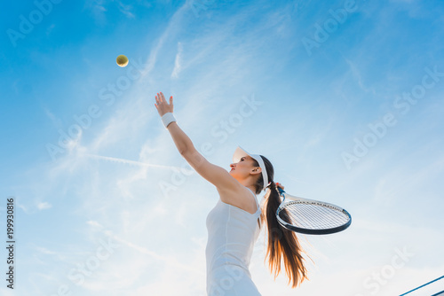 Woman playing tennis giving service throwing ball in the air © Kzenon