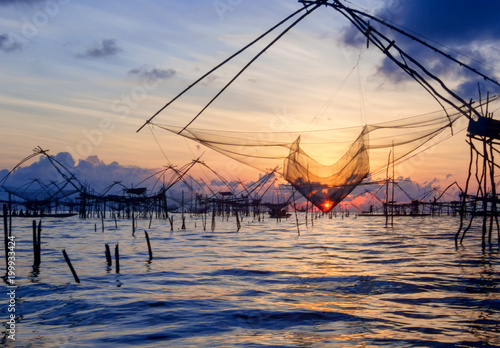 Sunrise at Pak Pra lake, Pattalung, Thailand,silhouette of traditional fishing method using a bamboo square dip net. © Sakkarin