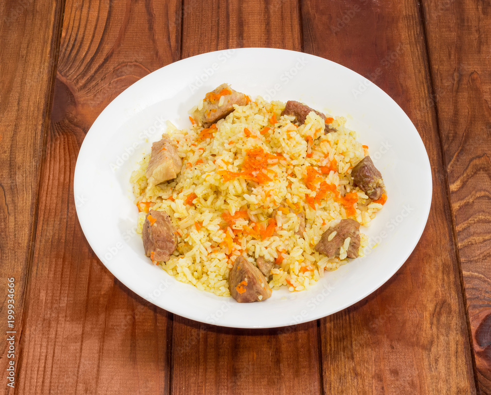 Cooked pilaf on dish on wooden surface Cooked pilaf on dish on wooden surface