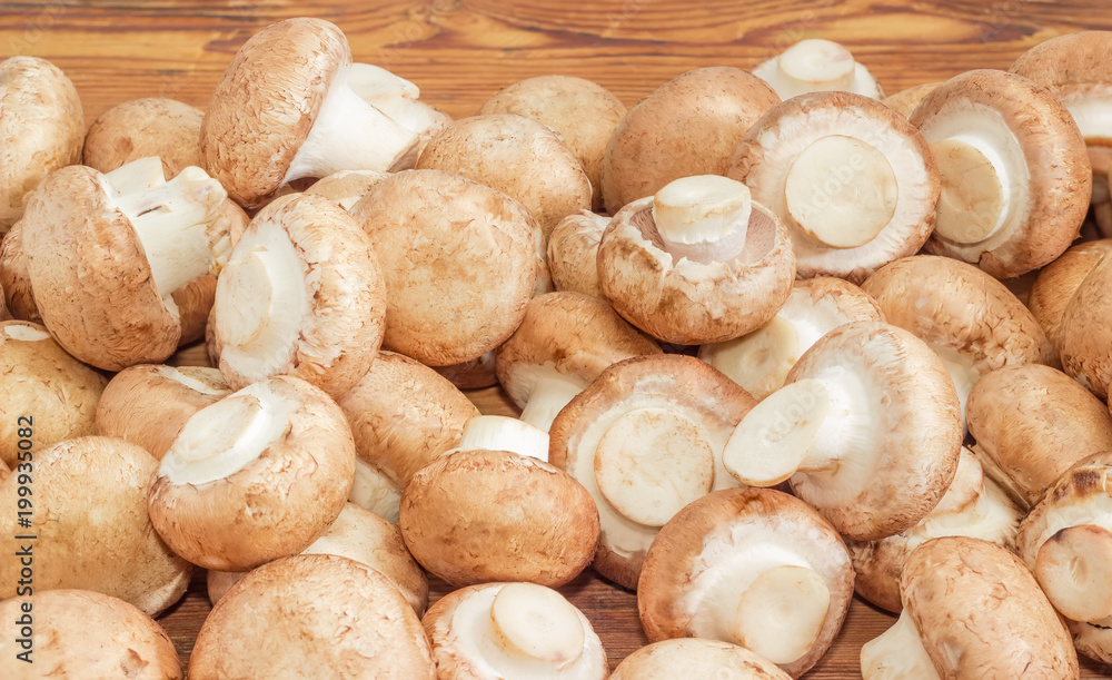 Pile of the raw brown mushrooms on wooden surface Pile of the raw brown mushrooms on wooden surface
