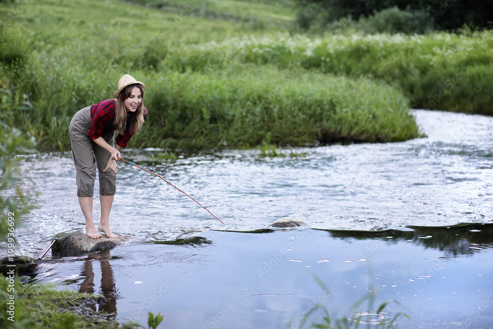 Fototapeta premium Girl by the river with a fishing rod