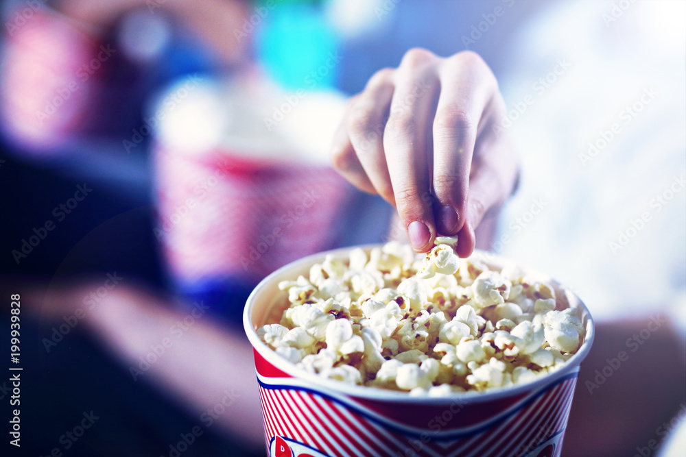 Male hand taking popcorn from the box in the cinema Male hand taking popcorn from the box in the cinema