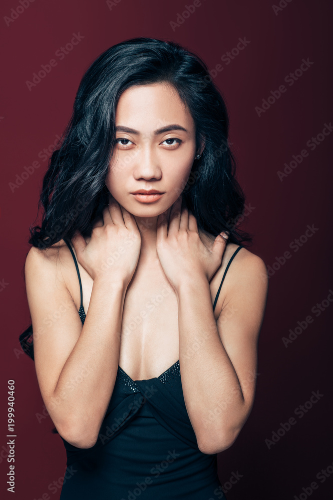 Young asian woman with hands on neck looking at camera