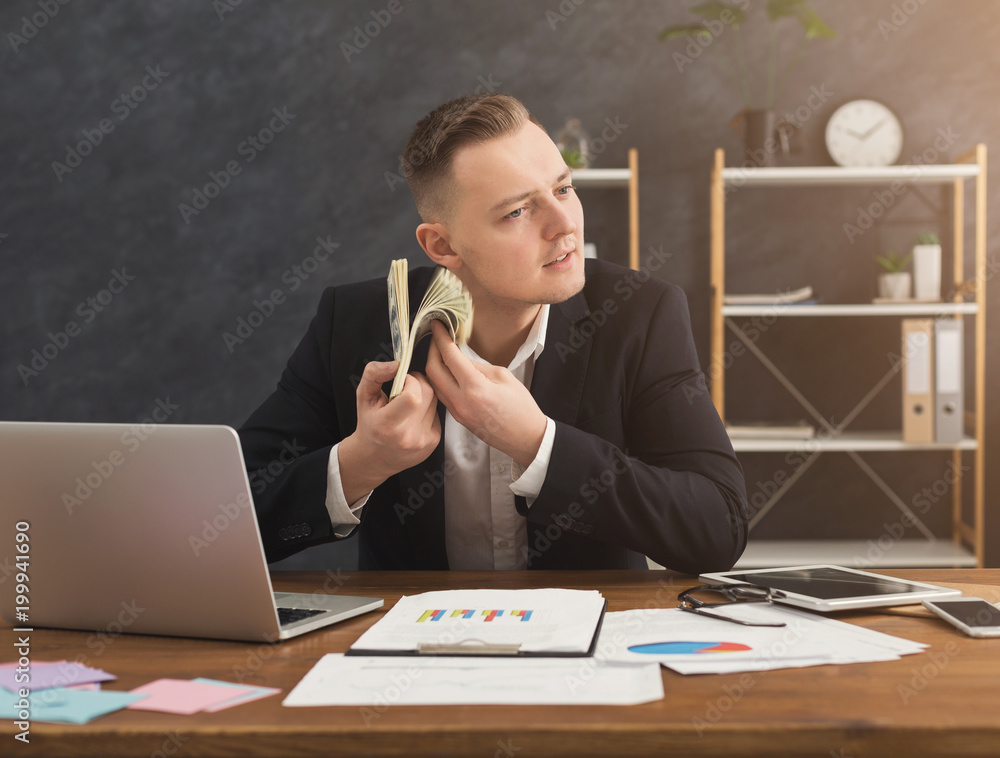 Financier man sitting in office and holding money in hand Financier man sitting in office and holding money in hand