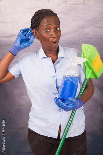 Photos Young cleaning lady with work tools listening