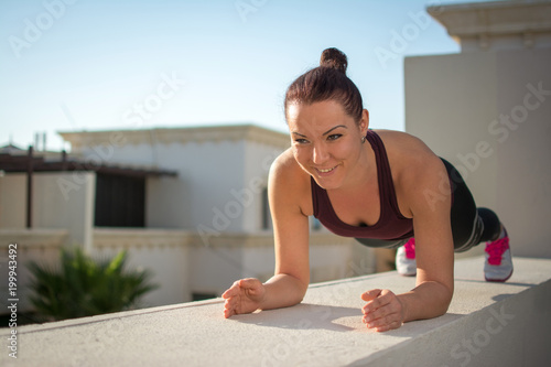 Young sporty woman in plank position outdoors
