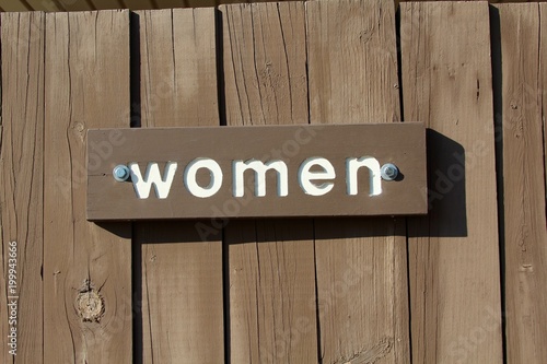 A wood women sign on the door and a close up view.