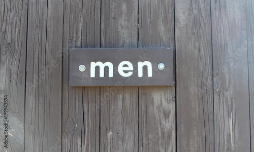 The men wood sign on the door and a close up view. 