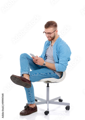 Young man sitting on chair and using mobile phone. Startupper. Young entrepreneur.