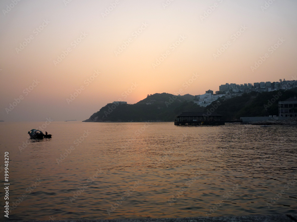 Peaceful sunset ocean view in Hong Kong. Small fish boat rowing slowly