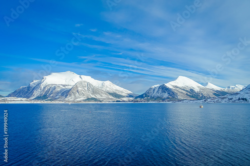 Amazing landscape of outdoor view of coastal scenes of huge mountain covered with snow on Hurtigruten voyage during a blue sky