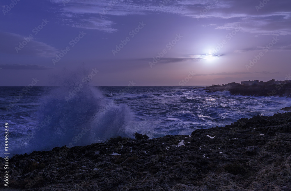 dark blue sunset. Coastline during rough sea. water splash.