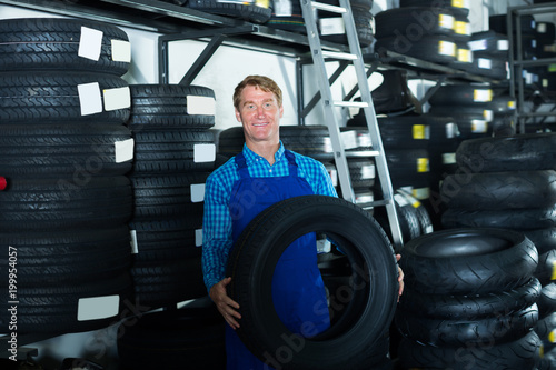Professional mechanic man standing with tires © JackF