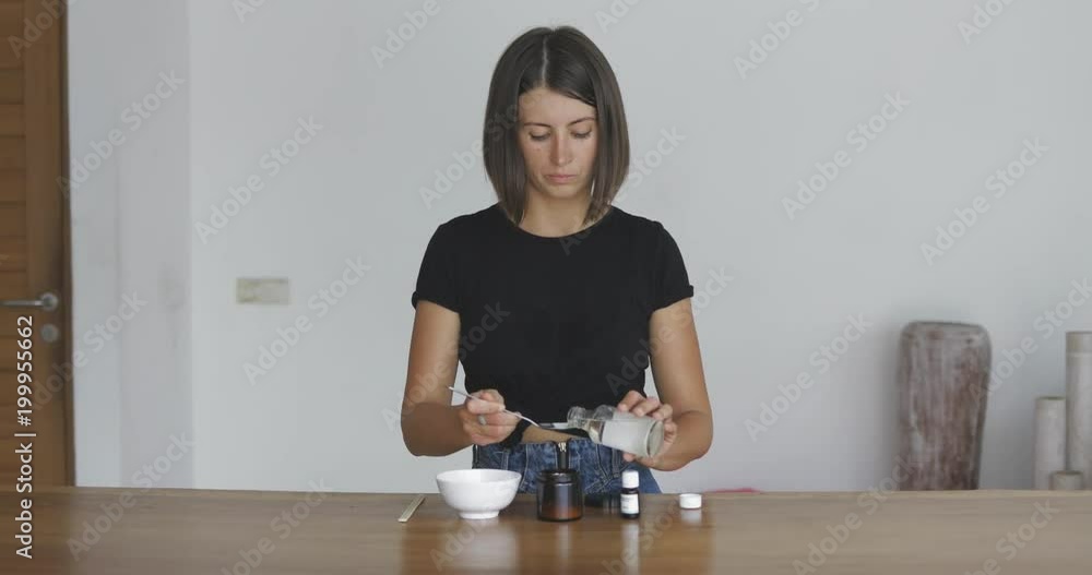 Young pretty woman makes toothbrush independently from ecological natural materials at home. Girl pours coconut oil into jar. Zero waste concept Young pretty woman makes toothbrush independently from ecological natural materials at home. Girl pours coconut oil into jar. Zero waste concept