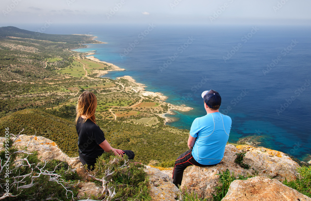 man and woman sitting on rock and looking at the Mediterranean Sea