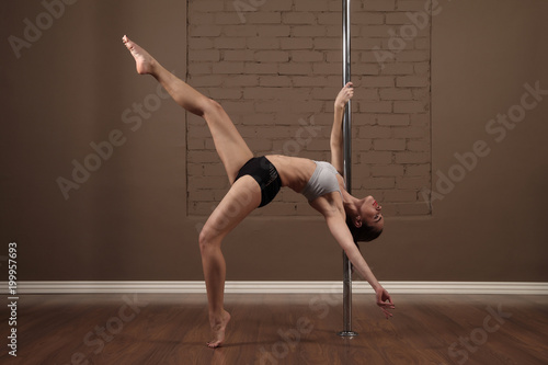 Sports girl doing acrobatics on a pole