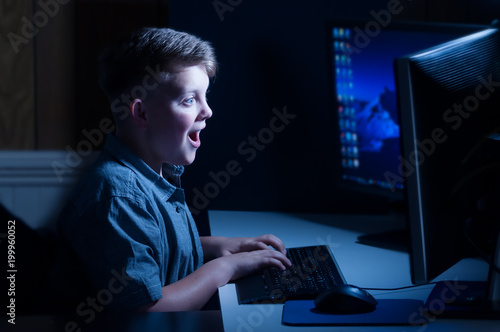 Young boy playing on computer happy face photo