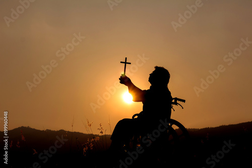 Silhouette disabled with wheelchair using cross to praise God,Trust concept,concept pray.