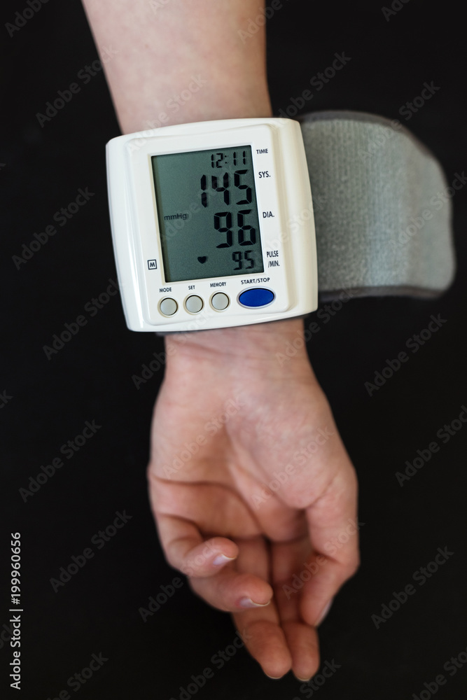 Woman hand with electric tonometer measuring blood pressure. Medicine, age, healthcare and people concept with tonometer and pills suggesting to take care of blood pressure. Woman hand with electric tonometer measuring blood pressure. Medicine, age, healthcare and people concept with tonometer and pills suggesting to take care of blood pressure.