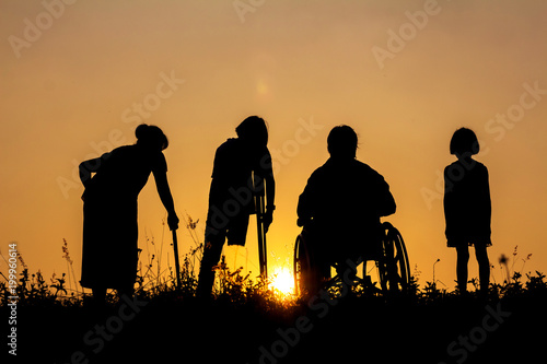 Wheelchair,Grandmother,Child,Feet disabled standing on hilltop relaxing joy view of mountain at sunnset time. photo