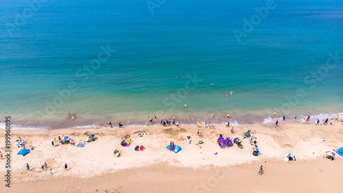 "Aerial view of sandy beach with tourists swimming in beautiful clear sea  water"