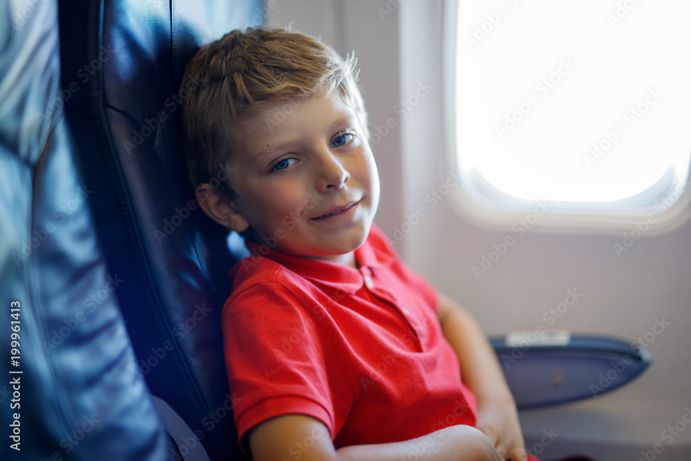 Little kid boy looking outside of plane window during flight on airplane. Little kid boy looking outside of plane window during flight on airplane.