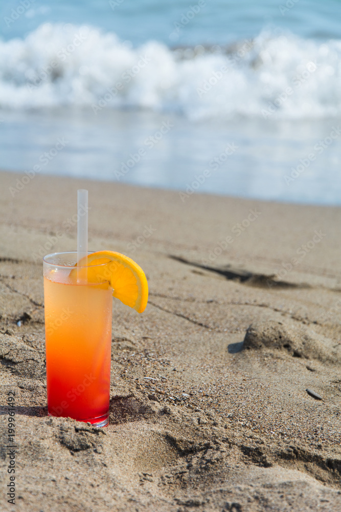 Glasses with colored cocktails on the beach with blue water in the background Glasses with colored cocktails on the beach with blue water in the background