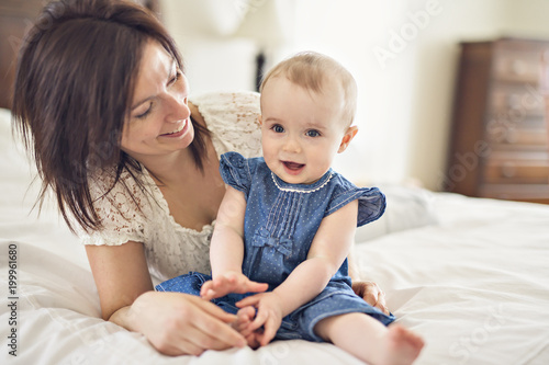 mother playing with her baby in the bedroom
