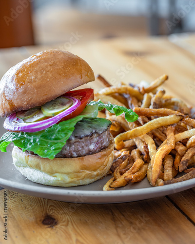 Burger with lettuce, tomato, onions and pickles with fries