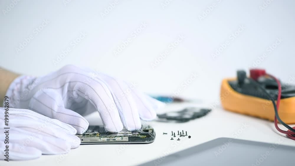 Professional IT engineer connecting a motherboard on a broken smartphone with care in a high-tech workshop. Professional IT engineer connecting a motherboard on a broken smartphone with care in a high-tech workshop.