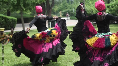 Three african women dancing folk dance in traditional costumes with coats of their skirts