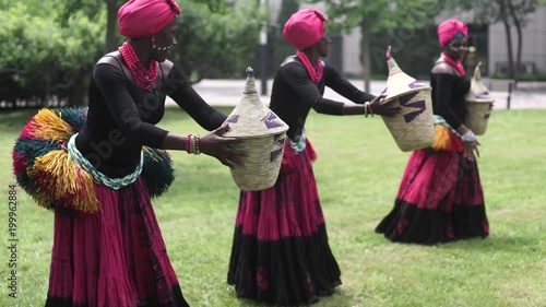 Three african women dancing folk dance in traditional costumes with coats of skirts