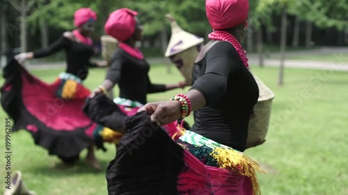 Three african women dancing folk dance in traditional costumes with coats of skirts. Three african women are dancing a folk traditional dance in traditional costumes with coats of their skirts. photo