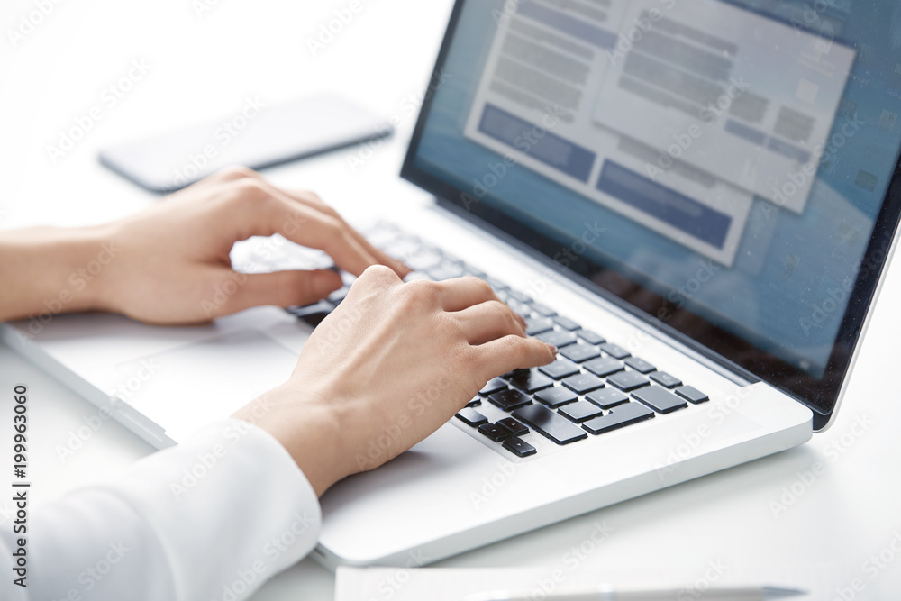 Typing on laptop keyboard. Close-up of a young woman holding brush in her hand and applying makeup. Isolated on light blue background. Typing on laptop keyboard. Close-up of a young woman holding brush in her hand and applying makeup. Isolated on light blue background.