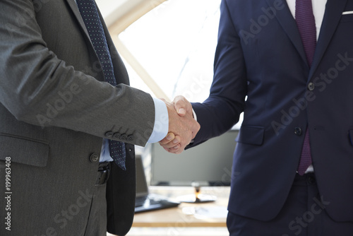 Handshake. Close-up shot of two businessman wearing suit and shaking hands. 