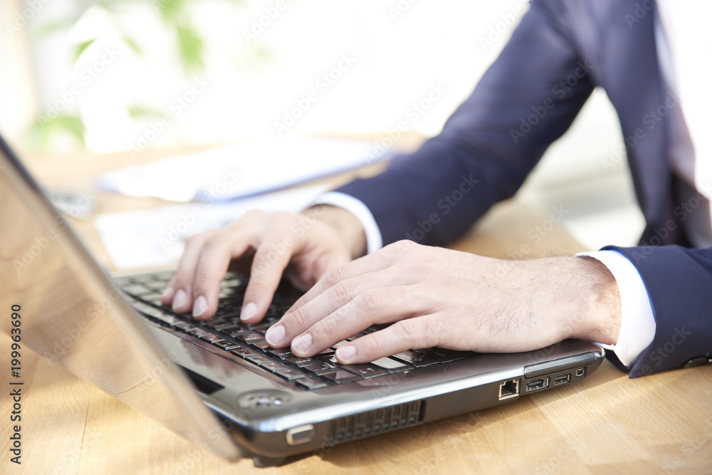 Close-up shot of businessman's hands while typing on keyboard. Professional man wearing suit while sitting at office desk and workin on laptop. Close-up shot of businessman's hands while typing on keyboard. Professional man wearing suit while sitting at office desk and workin on laptop.