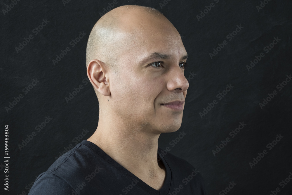 Obraz premium Profile portrait of a man with a shaved head, looking away from the camera