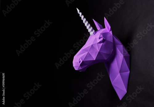 Photography Horizontal sideview of violet deep shadowed unicorn's head hanging on black smooth wall