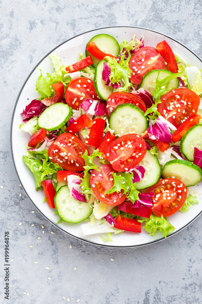 Fresh vegetable salad with tomatoes, cucumbers, sweet pepper and sesame seeds. Vegetable salad on white plate Fresh vegetable salad with tomatoes, cucumbers, sweet pepper and sesame seeds. Vegetable salad on white plate