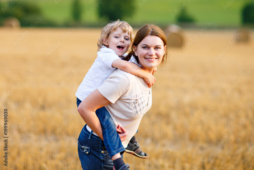 Mother holding kid boy on arms on wheat field in summer