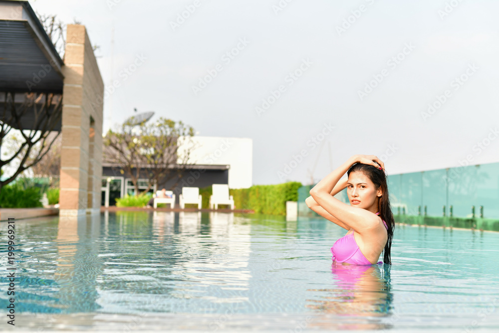 Swimsuit Concept. Beautiful girl wearing pink swimsuit. Beautiful girl in swimwear is relaxing at the swimming pool. Independent living sexy woman at the city center pool.