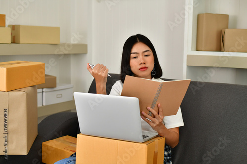 Sme business concept. Young Asian people are packing their packages.Delivery business  Small and Medium Enterprise (SMEs). Young man is working in the house.Young Owner Start up for Business Online. © S photographer