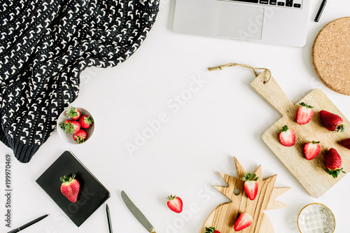 Frame of workspace with laptop, strawberry, notebook, cutting boards on white background. Flat lay, top view mock up.